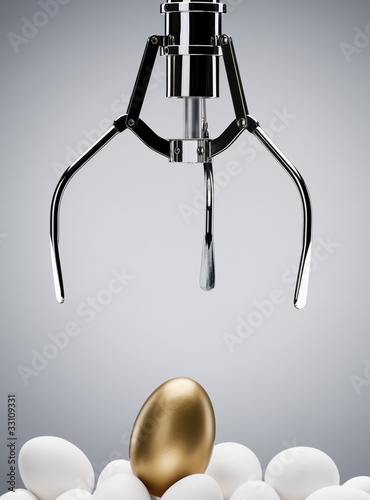 Photo: Mechanical claw reaching for golden egg Mechanical claw reaching for golden egg
