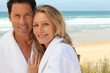 Couple stood by the sea wearing bathrobes