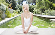 Woman sitting cross-legged by pond