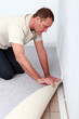 handyman is laying fitted carpet