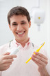 Man in dentist's office holding toothbrush and toothpaste