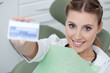 Woman in dentist's chair holding health insurance card