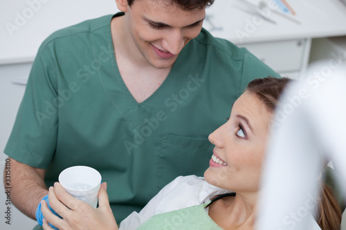 Photo: Dentist giving beaker to woman in chair Dentist giving beaker to woman in chair