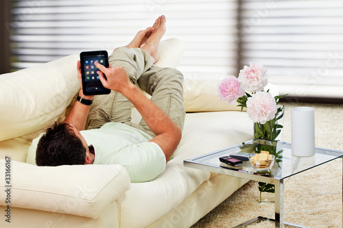 Foto: man relaxing in the living room, with tablet-pc man relaxing in the living room, with tablet-pc