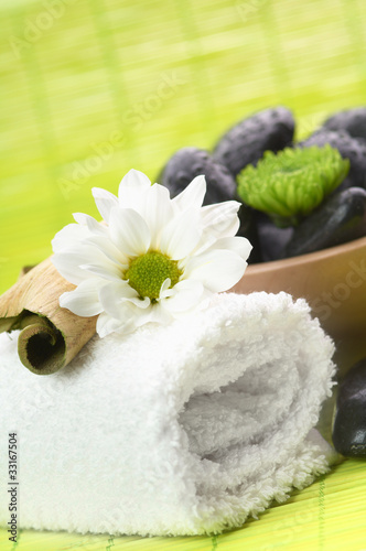 Photo: Spa, flower on the towel, and a bowl with black stones Spa, flower on the towel, and a bowl with black stones