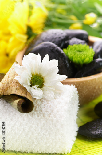 Photo: Spa, flower on the towel, and a bowl with black stones Spa, flower on the towel, and a bowl with black stones