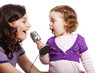 Mother and her little daughter sing into the microphone
