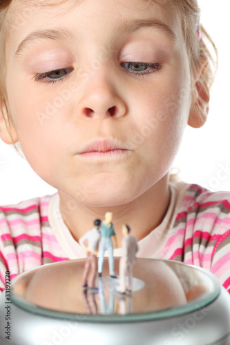 Photo: little girl carefully looks at small toy figures of people little girl carefully looks at small toy figures of people