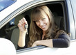Cheerful young lady sitting in a car and showing key Cheerful young lady sitting in a car and showing key