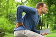 Young man in the park with back pain, steadicam shot