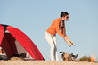 Camping happy woman making campfire on beach