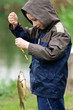Cute young boy with great smile holding carp and show a thumb up