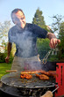 Freundlicher Mann beim Grillen hinter Rauschschwaden
