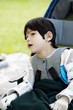 Four year old boy disabled with cerebral palsy sitting outdoors