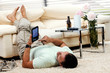 man relaxing in the living room, with tablet-pc, feet up