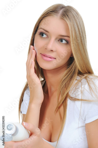 Photo: beautiful woman applying cream on her cheek beautiful woman applying cream on her cheek