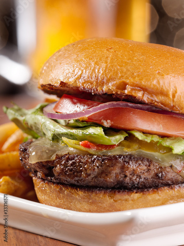 Photo: gourmet cheeseburger with mug of beer in background gourmet cheeseburger with mug of beer in background