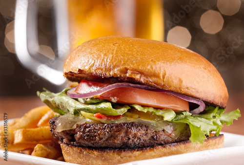 Foto: gourmet cheeseburger with mug of beer in background gourmet cheeseburger with mug of beer in background