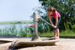 Mädchen spielt an der Wasserpumpe