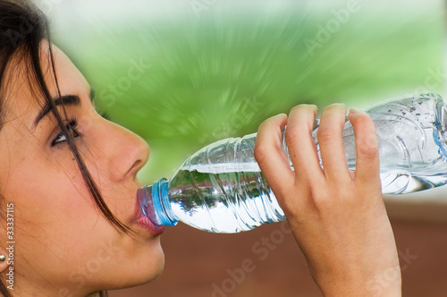 Photo: Mujer joven bebiendo agua de una botella Mujer joven bebiendo agua de una botella