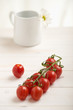 Photo: Cherry tomatoes on a white table, white flower in background Cherry tomatoes on a white table, white flower in background