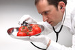 Arzt untersucht Tomaten mit Stethoskop auf Gefahr für Gesundheit