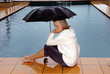 canvas print picture - Frau sitzt am Pool im Regen