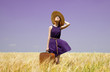 Redhead girl with suitcase at spring wheat field.