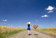 Lonely girl with suitcase at country road.