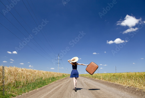 Photo: Lonely girl with suitcase at country road. Lonely girl with suitcase at country road.