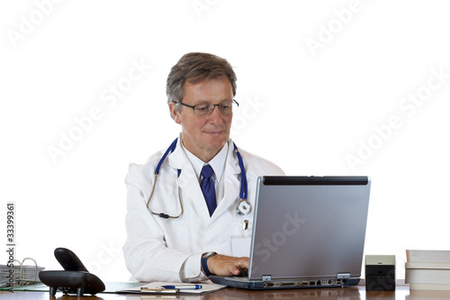 Foto: älterer sympathischer Arzt schreibt in Praxis an Patientenakte älterer sympathischer Arzt schreibt in Praxis an Patientenakte