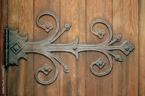Photo: Close-up Of An Ornamental Iron Hinge On An Old Wooden Door Close-up Of An Ornamental Iron Hinge On An Old Wooden Door