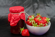 Glass pot with strawberry jam against black background Glass pot with strawberry jam against black background