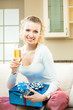 Young happy smiling woman with champagne and gifts at home