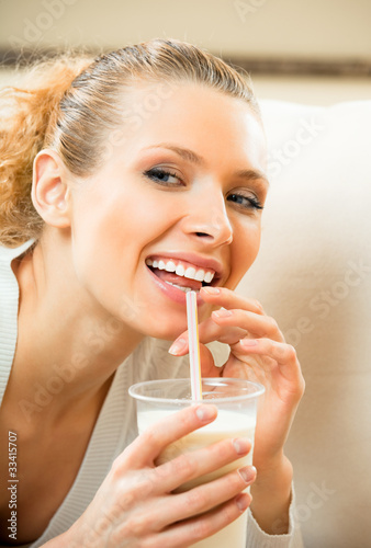 Photo: Young happy smiling woman drinking milk at home Young happy smiling woman drinking milk at home