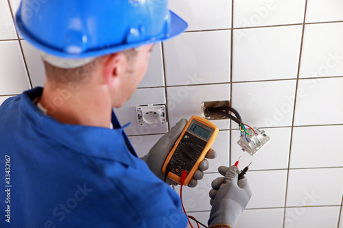 Photo: Electrician checking the wiring of a wall socket Electrician checking the wiring of a wall socket