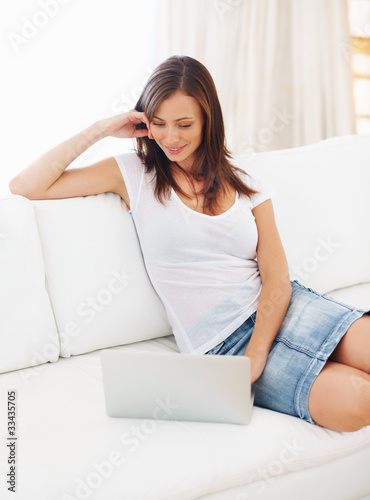 Photo: Happy young woman working on laptop at home Happy young woman working on laptop at home