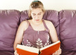 Teenager girl sitting on leather sofa and reading book