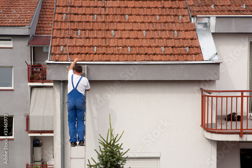 Photo: Man on a ladder climbing on the roof Man on a ladder climbing on the roof