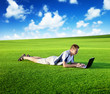 Young man use a notebook on green field