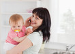 Good looking woman on the phone while holding her baby in her ar