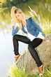 young woman sitting on stone at pond
