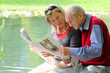 Großvater mit Enkelin beim Zeitung lesen im Grünen am Teich Großvater mit Enkelin beim Zeitung lesen im Grünen am Teich