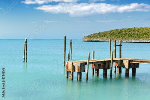 Photo: Mooring posts and pontoon leading in turquoise blue sea Mooring posts and pontoon leading in turquoise blue sea