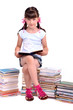 Schoolgirl sitting on the heap of books and reading