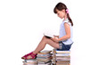 Little girl sitting on a big pile of books and reading