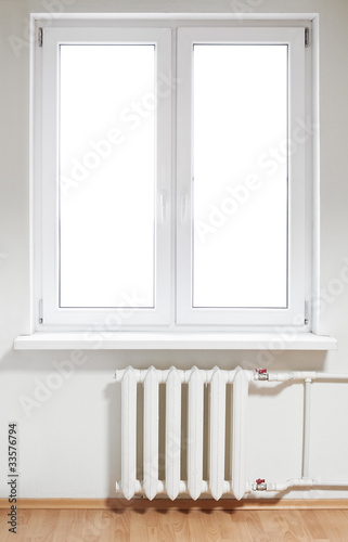 Photo : White plastic window with radiator under. Isolated on white White plastic window with radiator under. Isolated on white