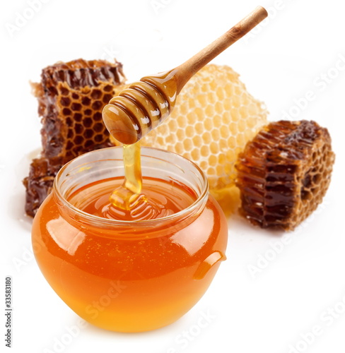 Foto: Pot of honey and wooden stick. Pot of honey and wooden stick.
