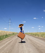 Lonely girl with suitcase at country road.