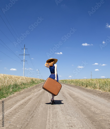 Photo: Lonely girl with suitcase at country road. Lonely girl with suitcase at country road.